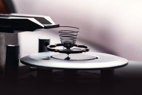 A titanium balance wheel with gold regulation screws and a silicon hairspring.
