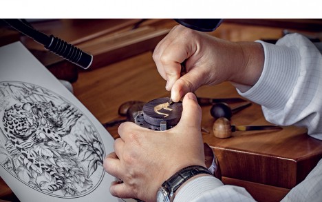 Engraving the gold applique depicting the clouded leopard.

